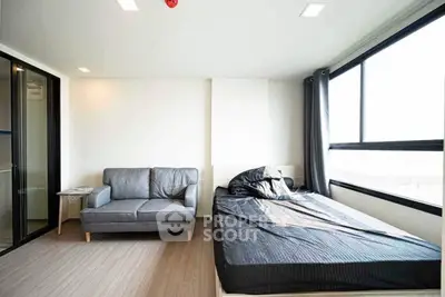 Modern bedroom with large windows and cozy sofa in a bright apartment.