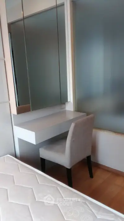 Modern bedroom with stylish vanity and comfortable chair, perfect for a cozy living space.