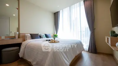 Modern bedroom with large window and stylish decor in a high-rise apartment.
