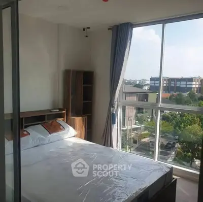 Bright bedroom with large windows offering a stunning city view, modern furnishings, and ample natural light.