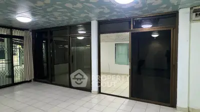 Spacious tiled room with large glass doors and windows, ideal for natural light and open living.