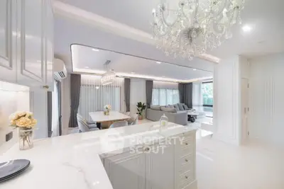 Luxurious open-plan living room with elegant chandelier and modern kitchen