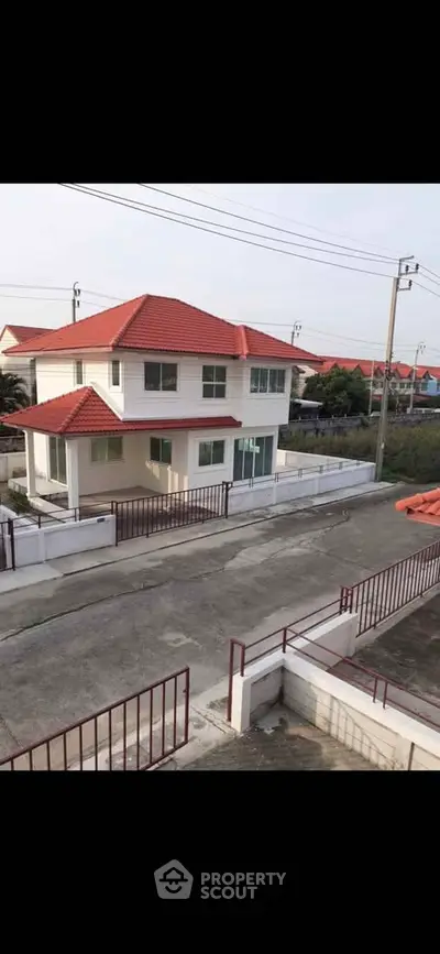 Charming two-story house with red roof and spacious driveway in a serene neighborhood.