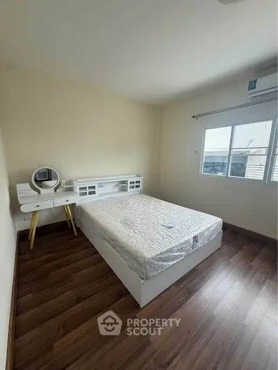 Spacious bedroom with modern furnishings and natural light, featuring a comfortable bed and stylish wooden flooring.