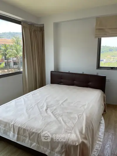 Cozy bedroom with large windows offering scenic views and natural light.