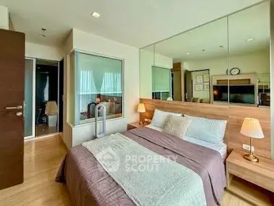Modern bedroom with cozy decor and mirrored wall in stylish apartment.