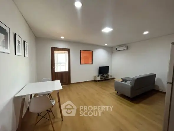 Spacious modern living room with wooden flooring and minimalist decor.