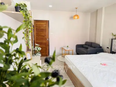 Cozy bedroom with modern decor, featuring a comfortable bed, stylish sofa, and lush indoor plants.
