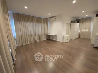 Spacious modern living room with wooden flooring and elegant curtains