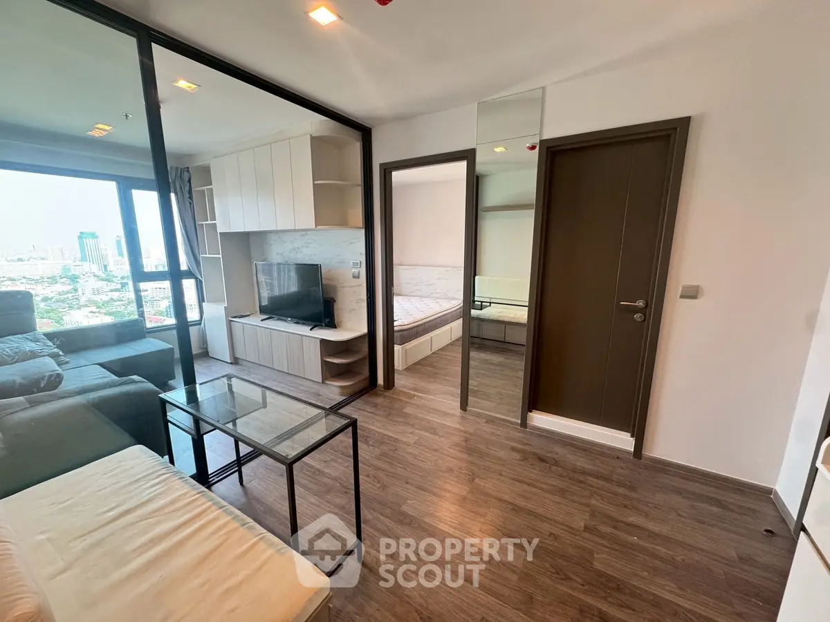 Modern apartment interior with city view, featuring cozy living room and bedroom with glass partition.