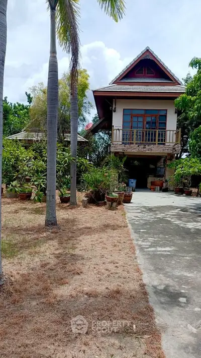 Charming elevated house with lush garden and driveway, perfect for serene living.