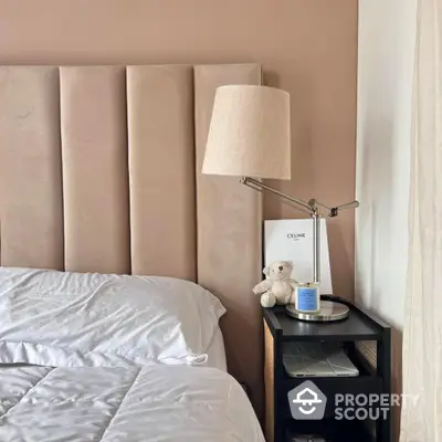 Cozy bedroom corner with plush headboard and stylish lamp