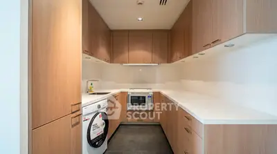 Modern kitchen with sleek wooden cabinetry and built-in appliances in a contemporary apartment.