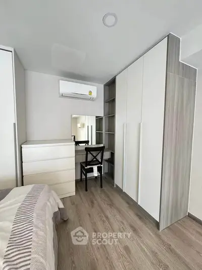 Modern bedroom with sleek furniture and built-in wardrobe, featuring a cozy workspace.