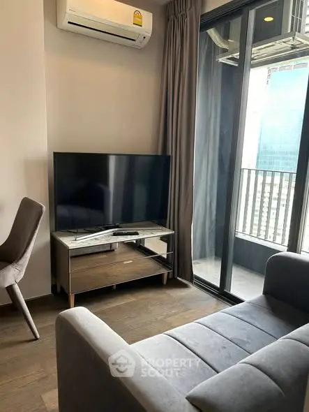 Modern living room with sleek furniture and city view balcony in high-rise apartment.