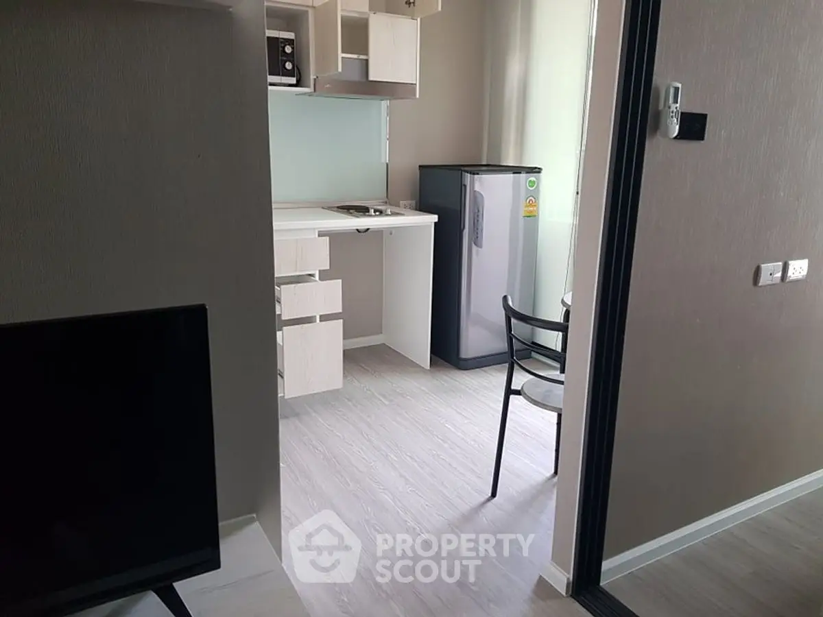 Modern compact kitchen with fridge and sleek cabinetry in a stylish apartment