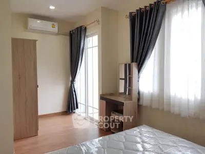Bright bedroom with modern furniture and large windows for natural light.