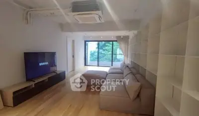 Spacious living room with modern sofa and large TV, featuring a serene balcony view.