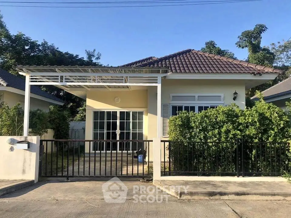 Charming single-story house with tiled roof and gated driveway in a serene neighborhood.