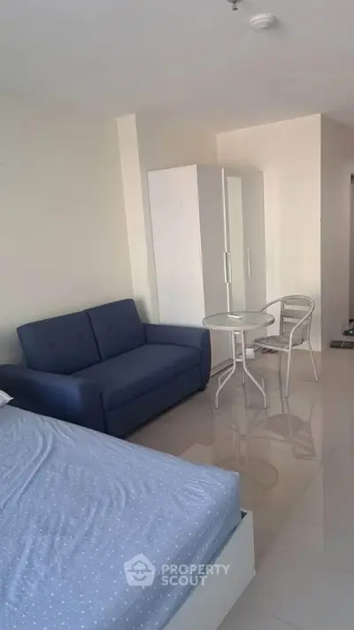 Modern studio apartment with sleek furnishings and glossy tiled floors, featuring a cozy sofa and compact dining area.