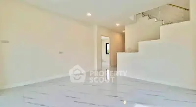 Spacious modern interior with sleek white flooring and staircase, perfect for contemporary living.