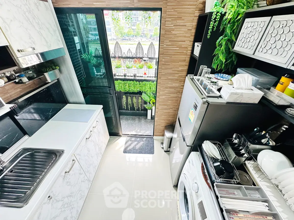 Modern kitchen with sleek appliances and balcony view, featuring marble countertops and ample storage.