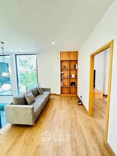 Spacious modern living room with wooden flooring and large windows offering natural light.