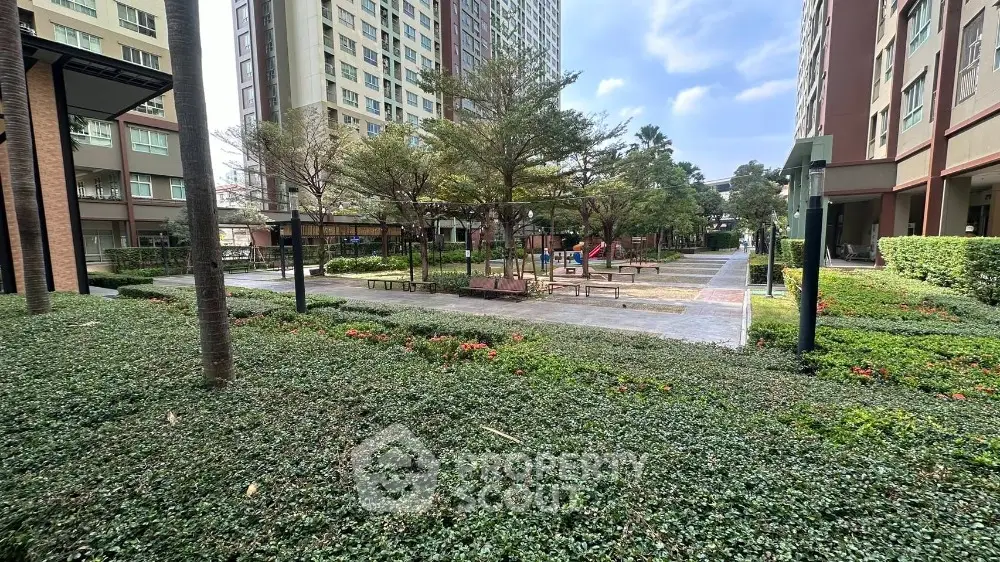 Modern residential complex with lush green garden and playground area.