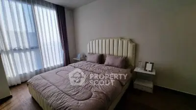 Elegant bedroom with plush bedding and natural light through large window, perfect for relaxation.