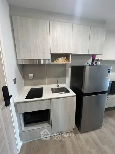 Modern compact kitchen with sleek cabinetry and stainless steel appliances in a stylish apartment.