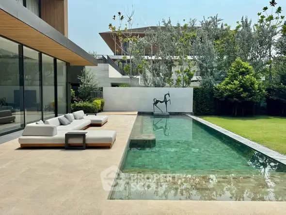 Luxurious modern home with sleek pool and elegant outdoor seating area.