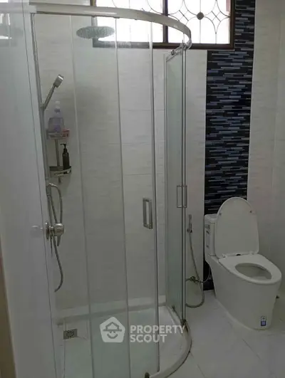 Modern bathroom with glass shower enclosure and sleek toilet design.