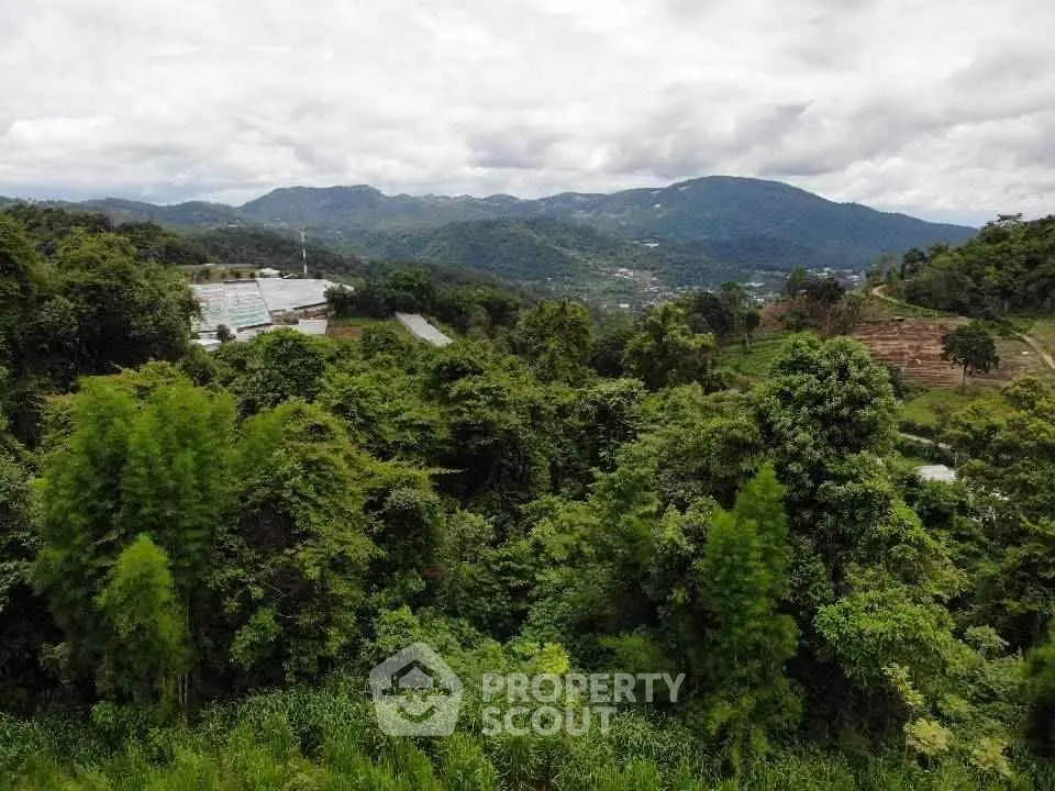 Scenic mountain view with lush greenery and distant hills, perfect for serene real estate development.