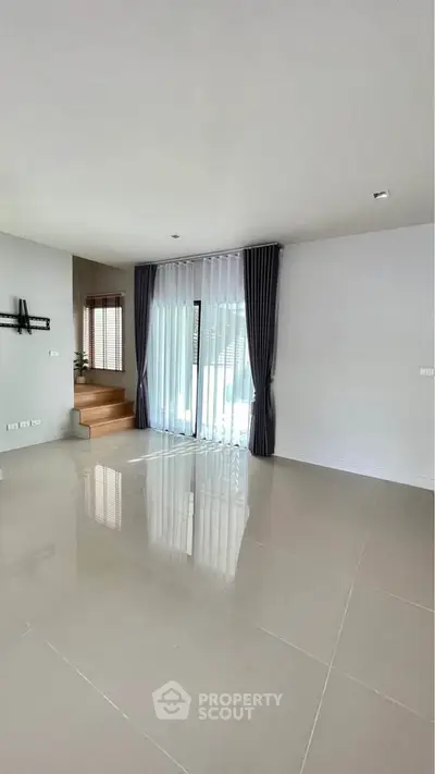 Spacious modern living room with large windows and elegant curtains.