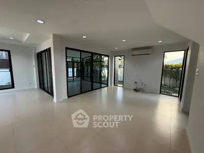 Spacious modern living room with large windows and garden view, perfect for family gatherings.