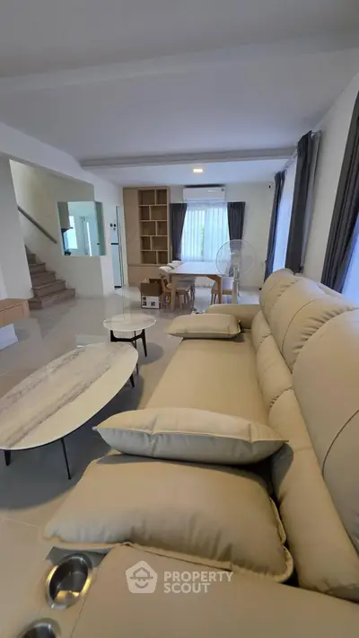 Spacious modern living room with elegant sofa and dining area, perfect for family gatherings.