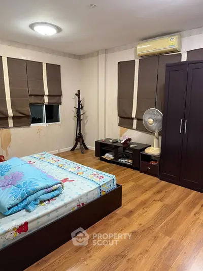 Spacious bedroom with wooden flooring and modern furnishings in a cozy home.