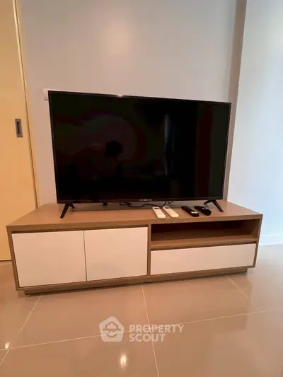 Modern living room with sleek TV stand and large flat-screen TV, perfect for entertainment.