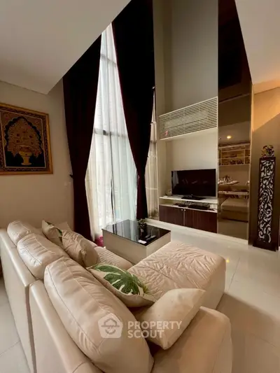Luxurious high-ceiling living room with elegant decor and large windows.