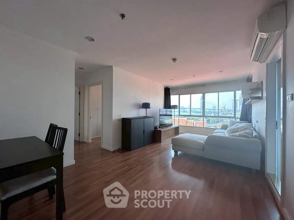 Spacious living room with large windows and wooden flooring, perfect for modern living.