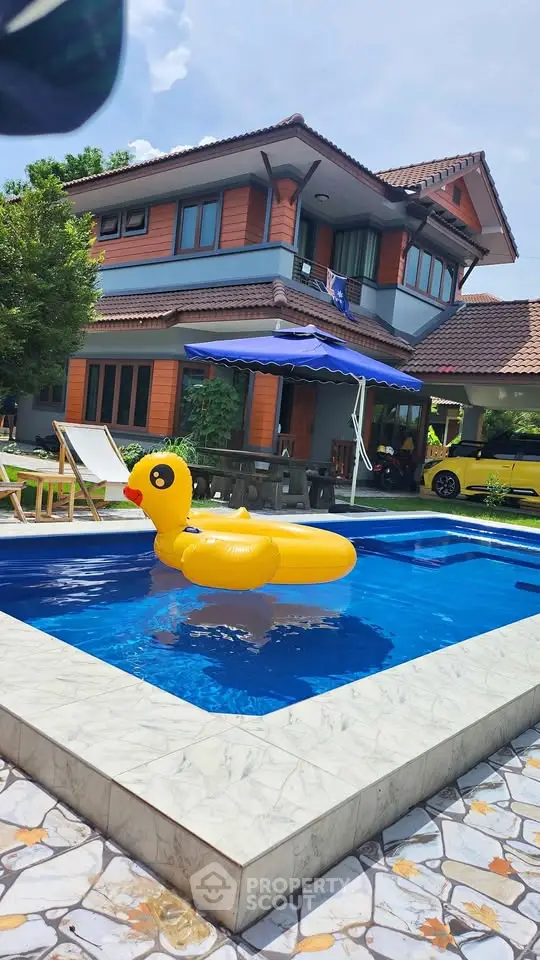 Charming two-story home with pool and inflatable duck, perfect for family relaxation.