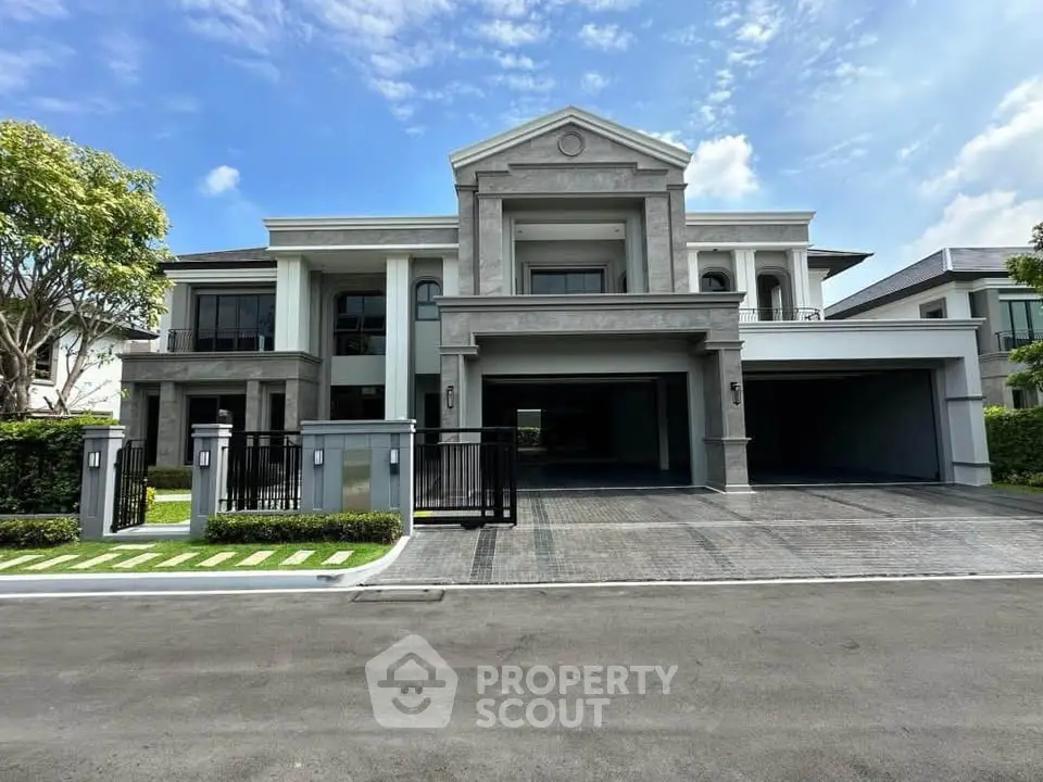 Luxurious modern mansion with grand entrance and spacious driveway under clear blue sky.