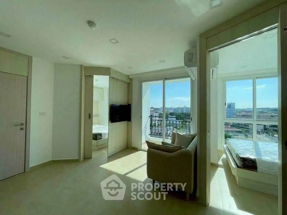 Bright modern apartment with large windows and city view, featuring a cozy living area and bedroom.