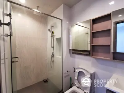 Modern bathroom with glass shower enclosure, sleek fixtures, and built-in cabinetry, showcasing a clean and contemporary design.