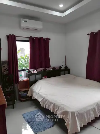 Cozy bedroom with modern decor and natural light, featuring air conditioning and stylish curtains.