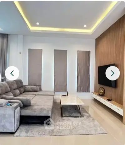 Modern living room with sleek design, featuring a cozy sectional sofa, wall-mounted TV, and elegant lighting.