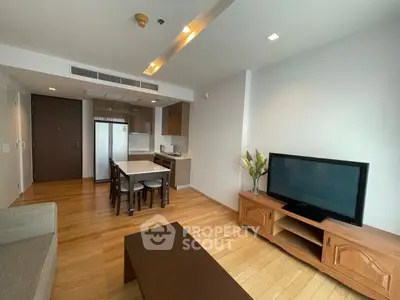 Modern living room with open kitchen, wooden flooring, and stylish furniture in a cozy apartment.
