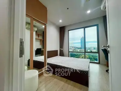 Modern bedroom with large window offering stunning city view and natural light.