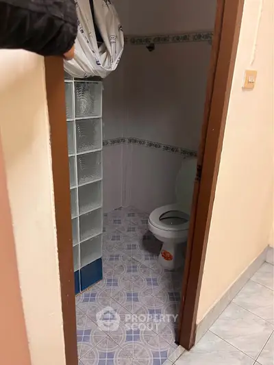 Compact bathroom with tiled floor and glass block partition