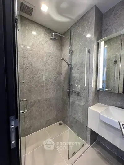 Modern bathroom with sleek glass shower and elegant gray tiles